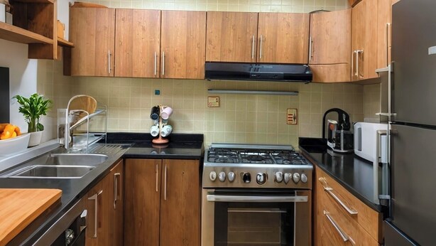 A kitchen with wooden cabinets, a gas stove, an oven, a sink, and a refrigerator.