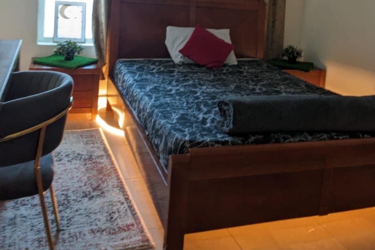 A bedroom with a wooden bed, a desk, and a window with curtains.
