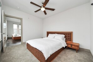 Ein Schlafzimmer mit Bett, Holz-Kopfstütze, Nachttisch und Deckenventilator.