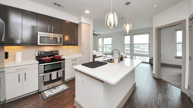A modern kitchen with dark cabinets, stainless steel appliances, and pendant lighting. - Prime Houston 2BR/2BA Galleria + RiverOaks Location (Houston)