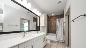 A modern bathroom with a large mirror, two sinks, a toilet, and a shower area. - Prime Houston 2BR/2BA Galleria + RiverOaks Location (Houston)