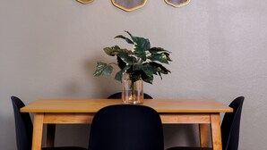 Un espace repas comprenant une table en bois, des chaises noires, un luminaire suspendu et des miroirs fixés au mur.