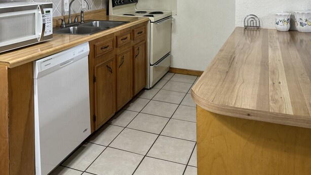 A kitchen with wooden cabinets, a microwave, a sink, a stove, and a dishwasher. - Contractor / Plant Workers Specialty (Sulphur)