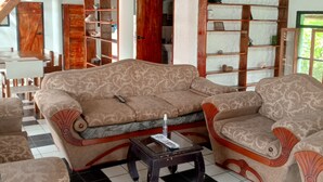 Ein Zimmer mit einer gemusterten Couch, einem kleinen Tisch und einer Treppe.