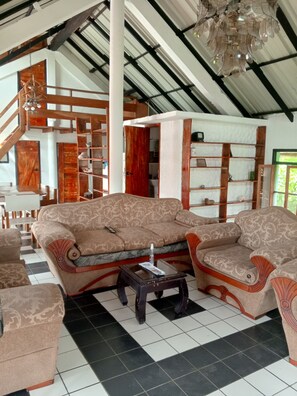 A room with a patterned sofa, a small table, and a staircase. - Spacious 4BR Galápagos Apartment | Sleeps 8 | AC | Full Kitchen | Garden (Puerto Baquerizo Moreno)