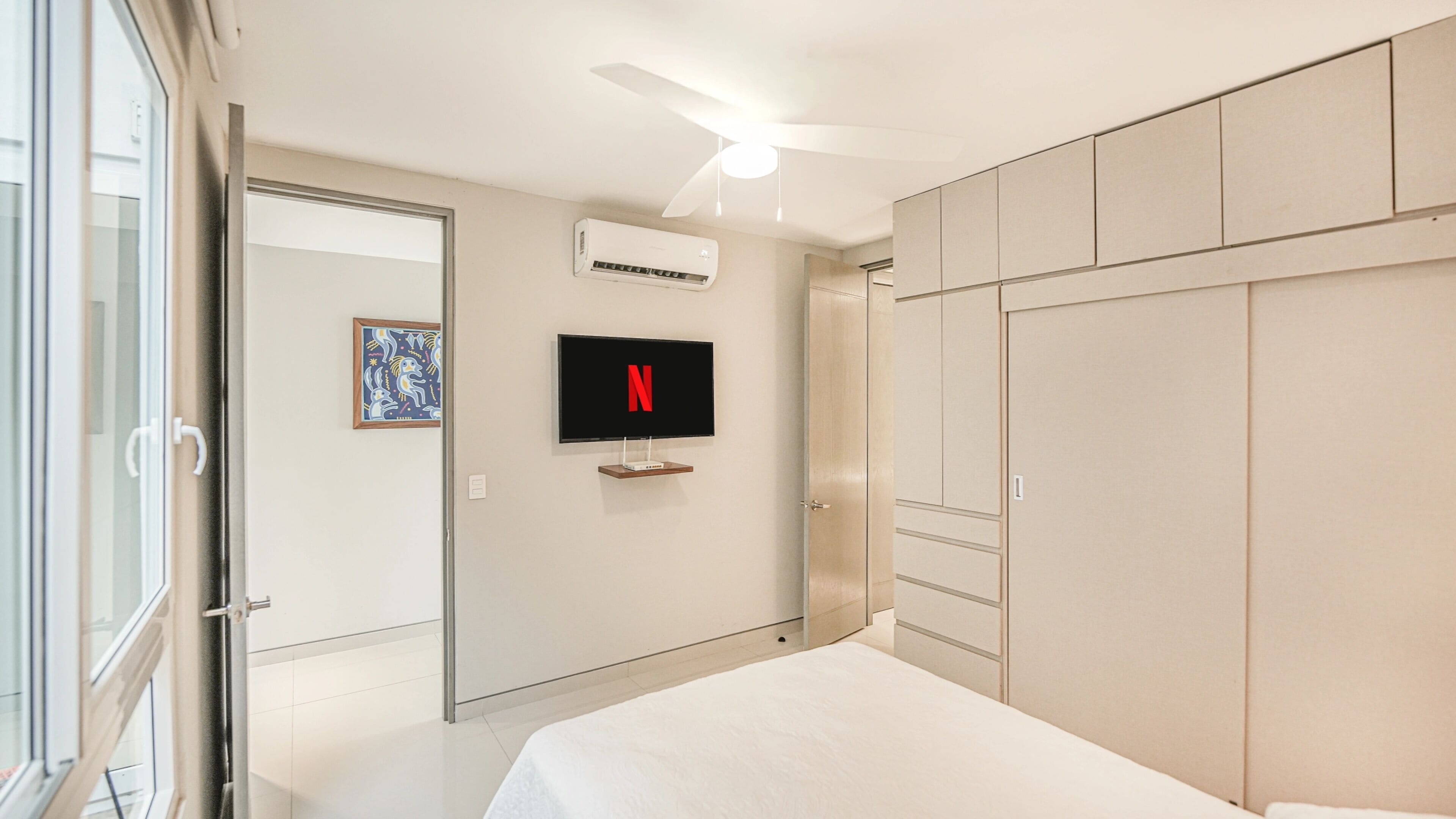 Ein modernes Schlafzimmer mit Bett, Kleiderschrank, Fernseher und Klimaanlage.