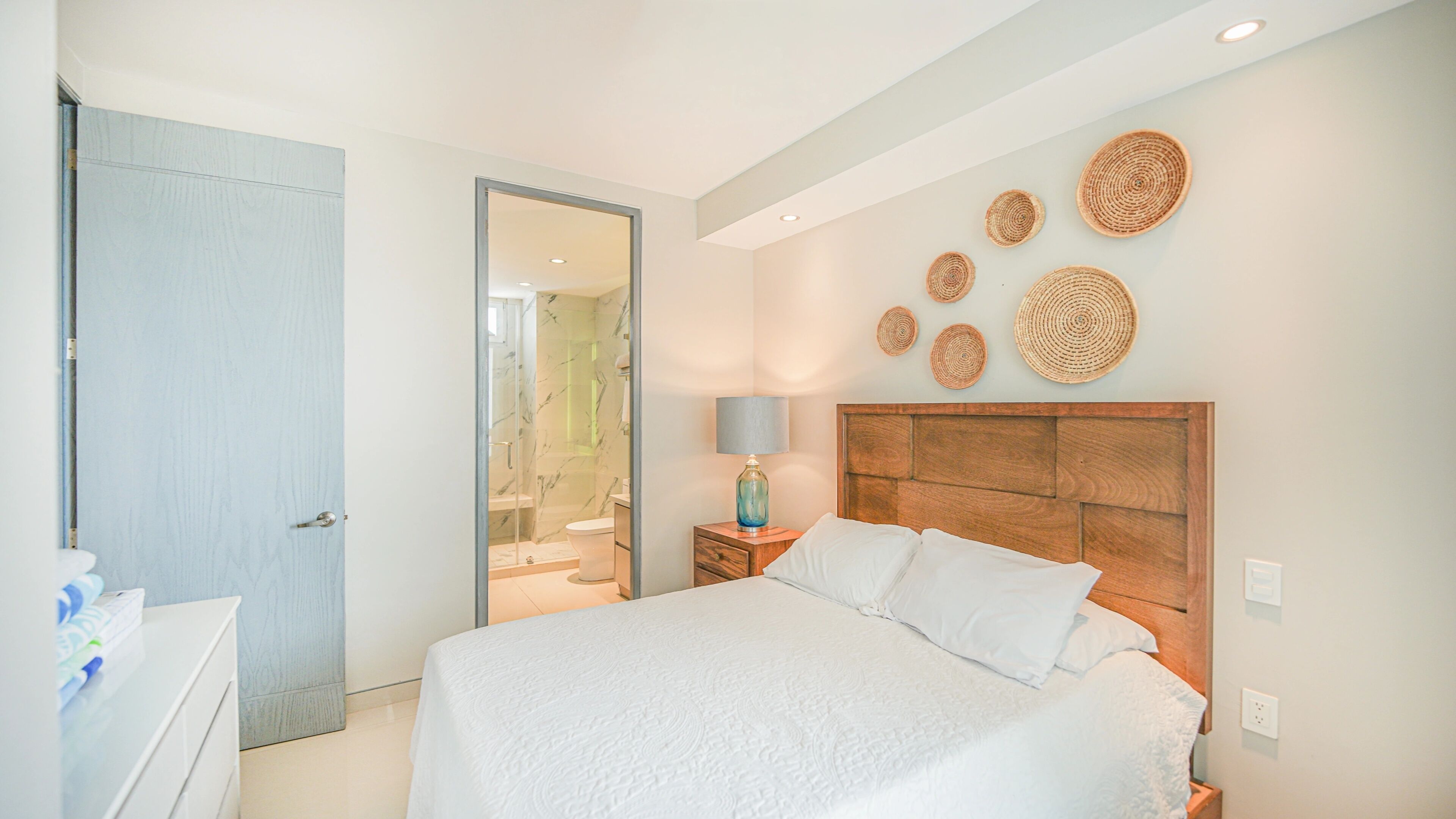 Une chambre à coucher comprenant un lit, une table de chevet, une lampe et un mur orné d’œuvres d’art murales de forme circulaire.