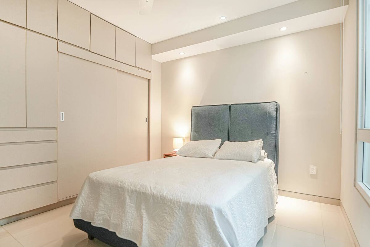 A bedroom with a bed, a wardrobe, and a window.