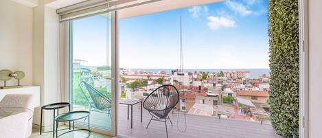 Un balcón con vista a la ciudad, una silla y una mesa.