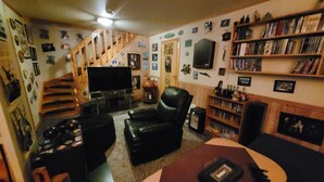 A living room with a fireplace, a bookshelf, a TV, and a staircase.