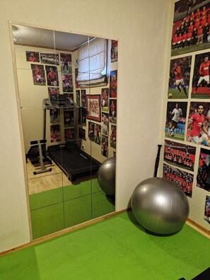 Ein Fitnessstudio mit Trainingsgeräten, einem Spiegel und Sportmemorabilien.