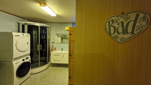 A laundry room with a washing machine, dryer, and a glass-enclosed dryer.