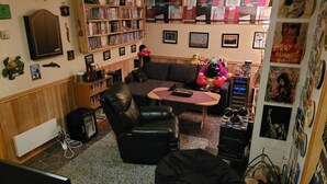A living room with a couch, chairs, a coffee table, a bookshelf, and various decorations.