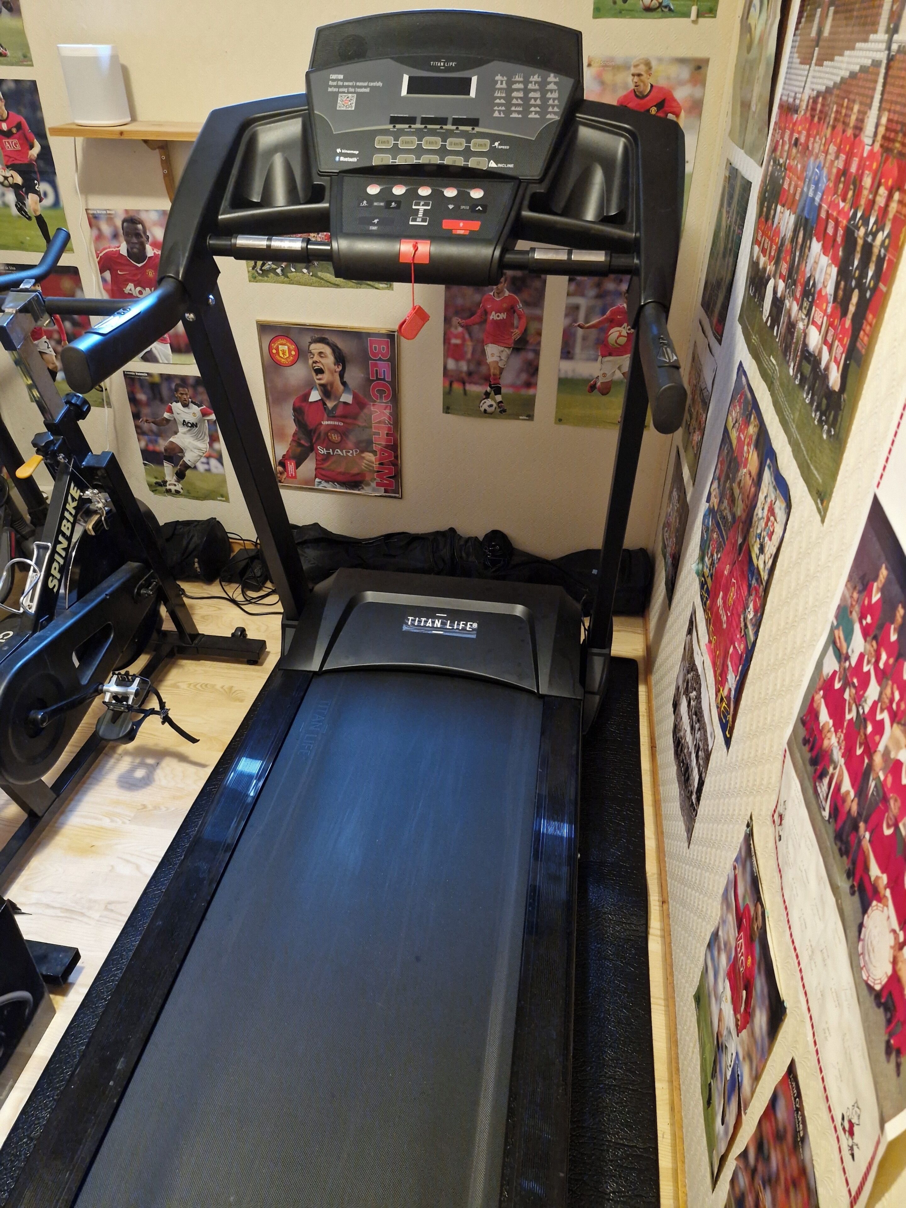 Un tapis de course doté d’un écran numérique, entouré de divers objets de collection liés au sport.