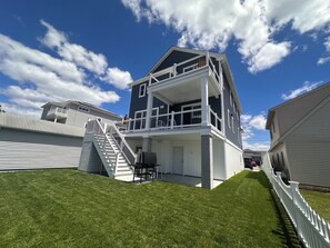 Ein zweistöckiges Haus mit Balkon, Treppe und einem gepflegten Rasen.