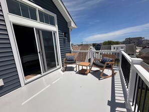 Ein Balkon mit Glastür, zwei Schaukelstühlen und einem kleinen Tisch.