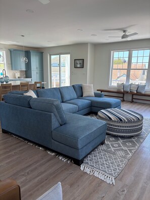 A modern living room with a sectional sofa, a dining area with a table and chairs, and a kitchen with blue cabinets. - Brand new 4 bedroom 3 Bath house 2 blocks to the beach in charming Brigantine (Brigantine)