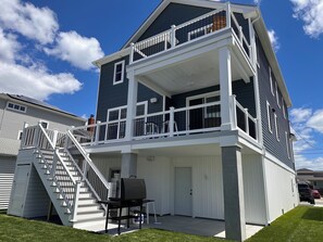 Et toetagers hus med balkon, grill og trappe op til øvre niveau.