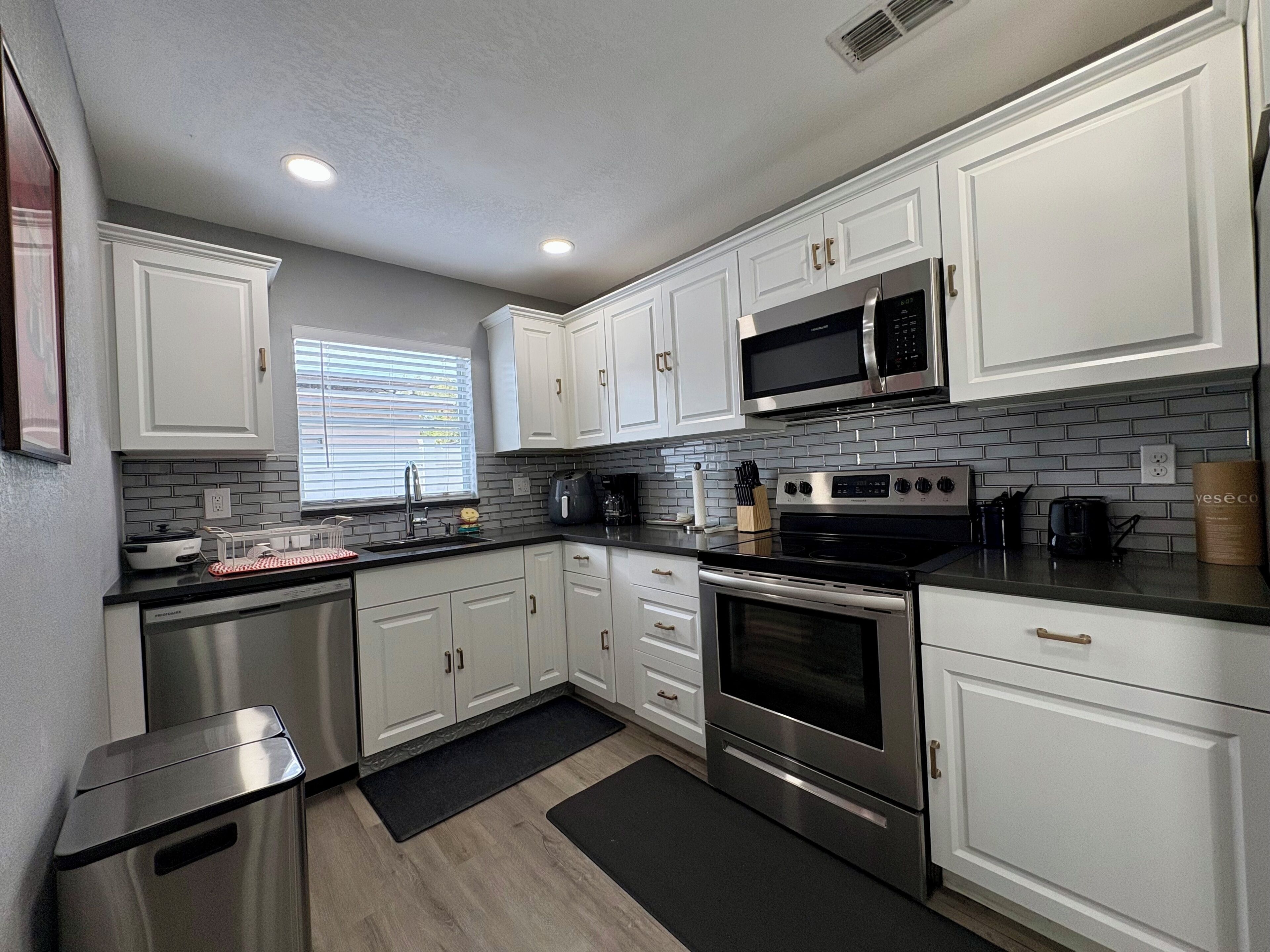 A modern kitchen with white cabinets, stainless steel appliances, and a black countertop.