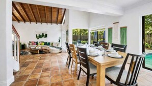 Un comedor con una mesa y sillas de madera, un sofá y vista a una piscina.