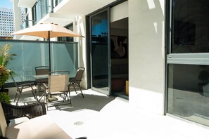 An outdoor seating area with a table and chairs, a large umbrella, and a potted plant. - NEW Apt with PATIO in Downtown | CP Collection (Miami)