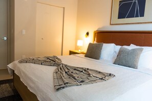 A neatly made bed with a patterned blanket, a wooden headboard, and a framed picture on the wall. - NEW Apt with PATIO in Downtown | CP Collection (Miami)