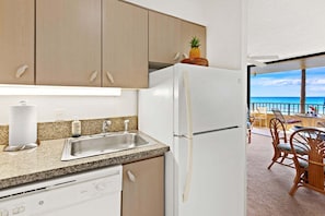 A kitchen with a stainless steel sink, a white refrigerator, and wooden cabinets. - New Listing! Oceanfront 2BR Maui Escape (Honokowai)