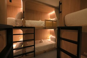 A bunk bed room with wooden walls, a small table, and a lamp. - Yen Hostel & Smoothies Silom (Bangkok)