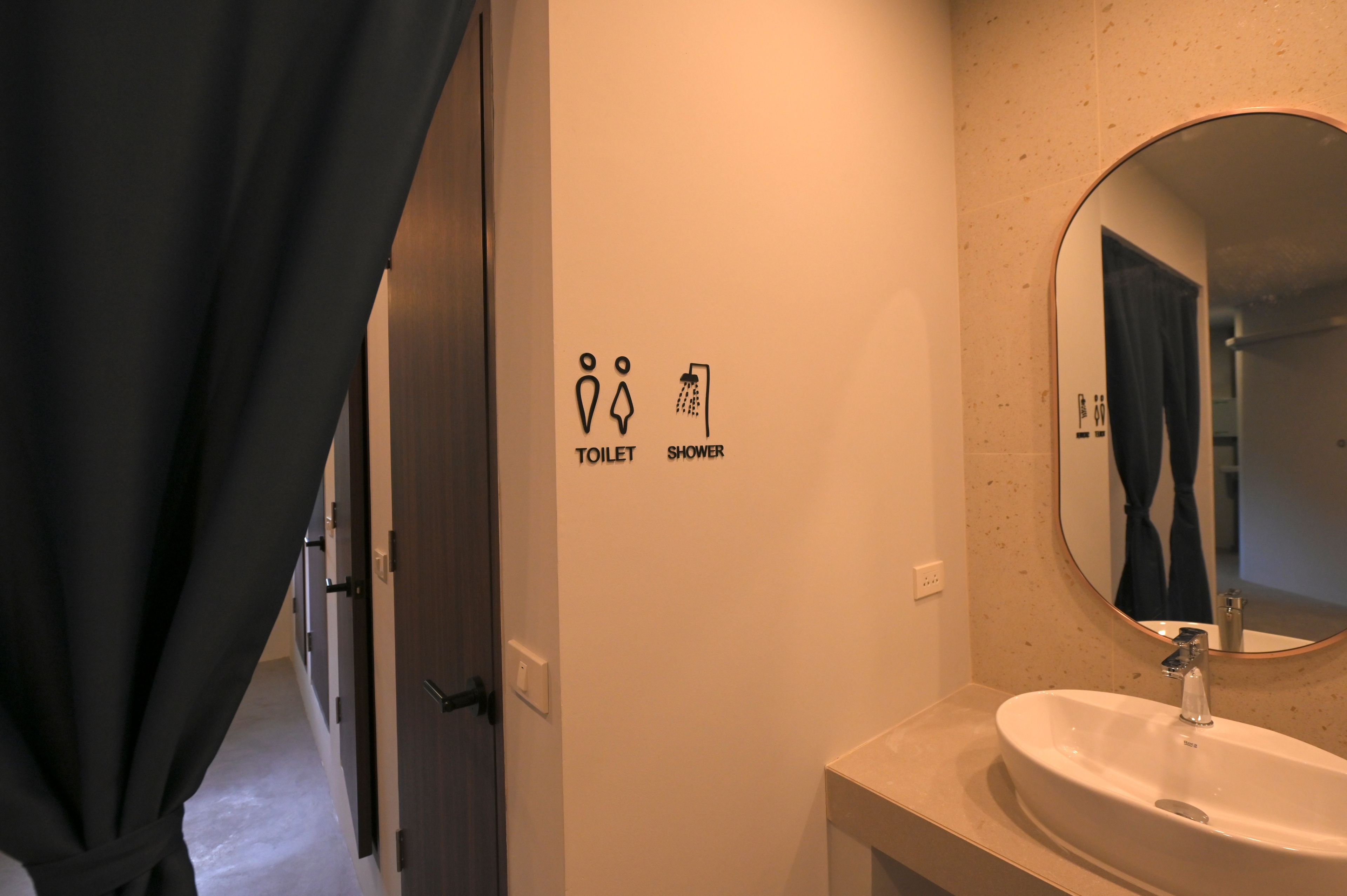 A bathroom with a white sink, a mirror, and a wall-mounted sign indicating a toilet and shower.