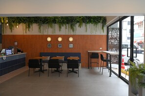 A modern cafe interior with a wooden wall, seating area, and a counter. - Yen Hostel & Smoothies Silom (Bangkok)