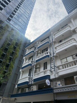 A multi-story building with balconies, air conditioning units, and a sign indicating the name 'Yen'. - Yen Hostel & Smoothies Silom (Bangkok)
