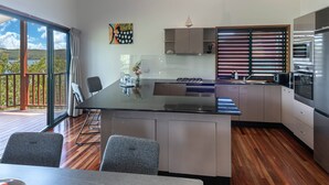 A modern kitchen with a central island, built-in appliances, and a view to the outside. - Casuarina Cove 6 (Hamilton Island)