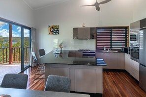 A modern kitchen with a central island, built-in appliances, and a view to the outside.
