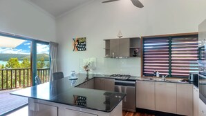 A modern kitchen with a central island, stainless steel appliances, and a view of the outdoors. - Casuarina Cove 6 (Hamilton Island)