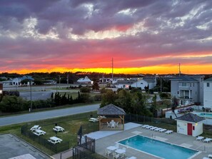 A residential area with a swimming pool, lounge chairs, and a gazebo. - Beacon Waves - Beach condo w/ Pool (Kill Devil Hills)