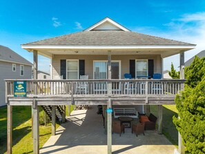 A two-story house with a covered porch, outdoor seating, and a sign for Seaside Vacations. - Rockin Robin - OBX beach retreat 3/min to beach (Kill Devil Hills)
