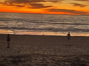 Ein Strand mit Wellen und einem Sonnenuntergang.
