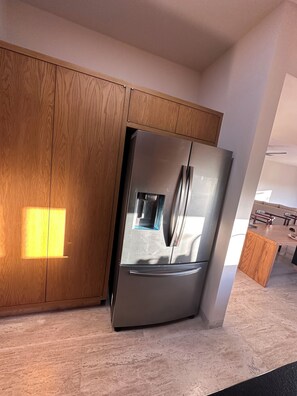Eine moderne Küche mit einem Edelstahlkühlschrank, Holzschränken und einer Marmorarbeitsplatte.