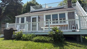Une maison à deux étages, avec une façade blanche, un porche couvert et une cheminée bien visible.