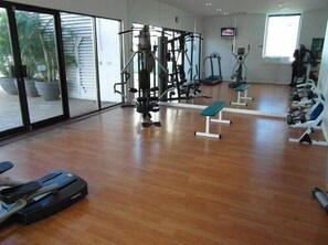 A gym with exercise equipment, a treadmill, and a television screen. - Comfortable City Stay with Views (Gold Coast)