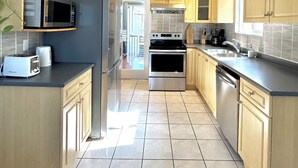 Une cuisine moderne avec des meubles en bois, des appareils électroménagers en acier inoxydable et un sol carrelé.
