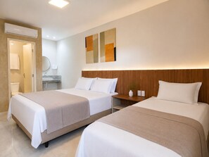 A hotel room with two beds, a wooden headboard, a bedside table, a mirror, and a wall-mounted air conditioner. - Exclusive Hotel (Campos Sales)