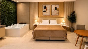 Una habitación de hotel moderna con una cama grande, una bañera, una mesa de comedor y una pared verde.