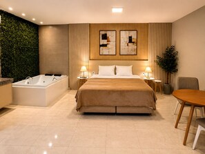 Een moderne hotelkamer met een groot bed, een badkuip, een eettafel en een groene wand.