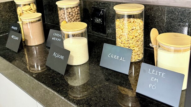 Una barra de desayuno con recipientes etiquetados de cereales, leche y otros productos para el desayuno.