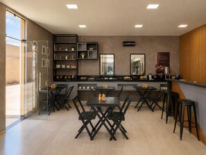 A modern kitchen with a central island, bar seating, and a view through a glass door. - Exclusive Hotel (Campos Sales)