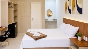 A hotel room with a bed, a desk, a chair, a wardrobe, a mirror, and a sink. - Exclusive Hotel (Campos Sales)