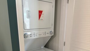 Eine kompakte Wascher- und Trockner-Kombination mit Bedienfeld, Warnhinweis und Abluftschlitz für den Trockner.