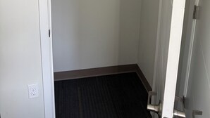 Ein geschlossener Kleiderschrank mit Metallstange, einer Tür mit Griff und einem Teppichboden.