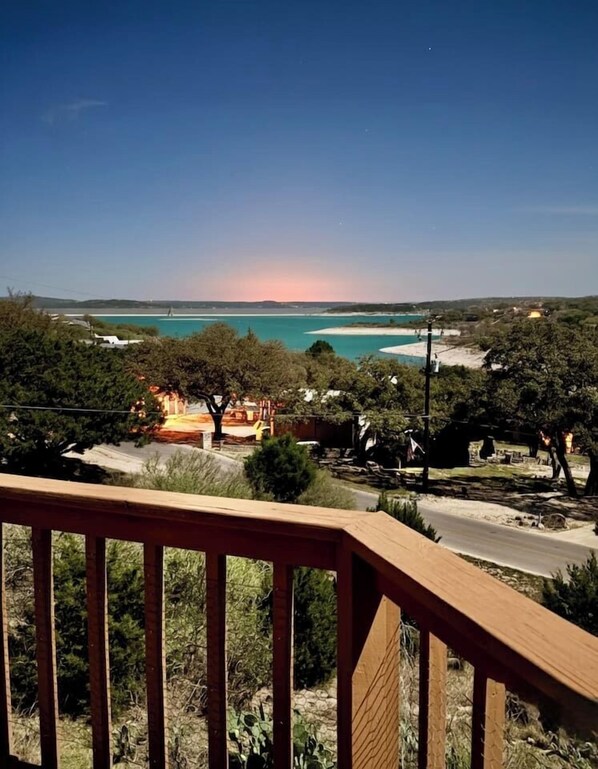 Eine Küstenlandschaft mit einer Holzterrasse, Bäumen und Blick auf das Meer.